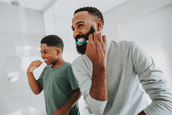 Father brushing teeth with son