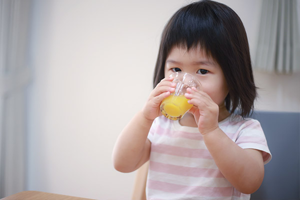 Small child drinking orange juice