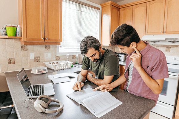 Father helping teenage son with homework