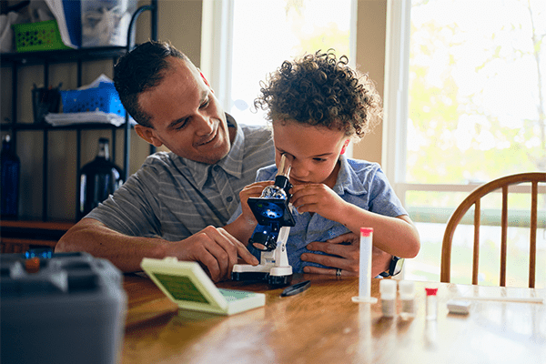 Father and son using microscope