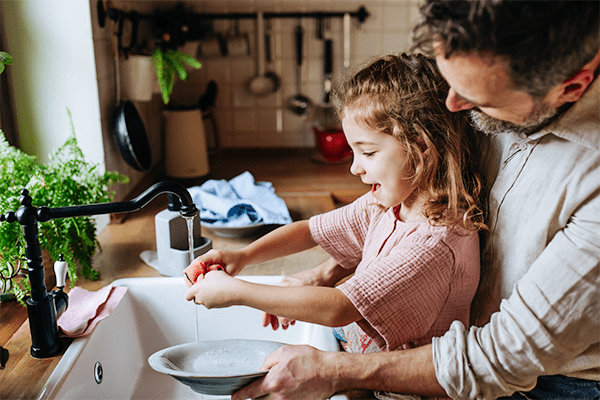 Father teaching daughter to wash dishes